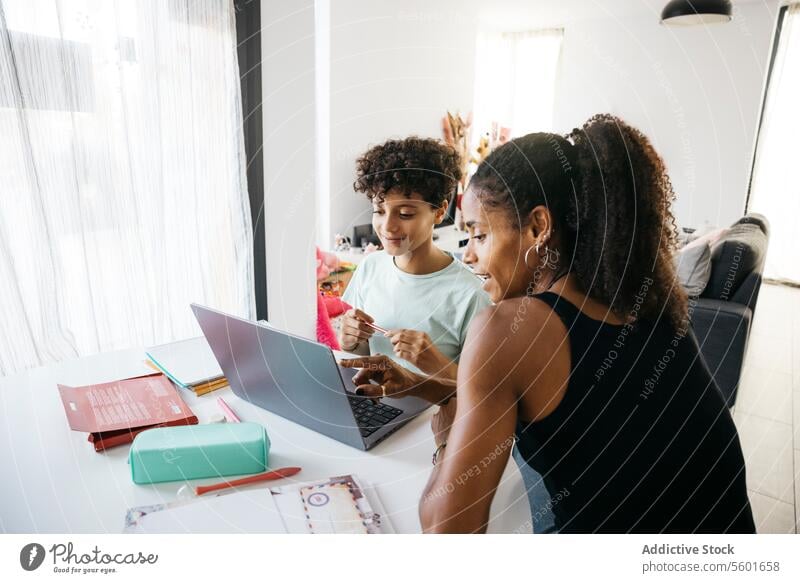 Girl doing her homework with mother Culture Family adorable affectionate after school bonding book cheerful child childhood children cute daughter day