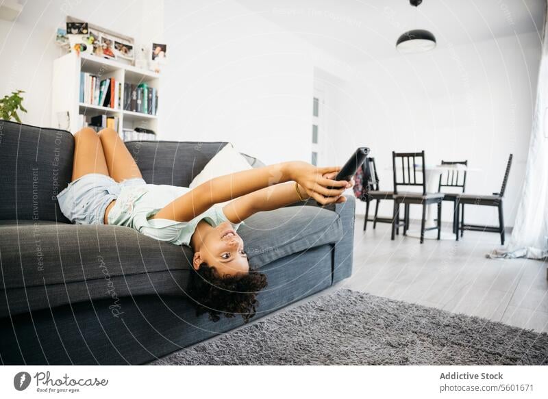 Girl watching tv in living room Family Preteen daughter Tv Tv controller adorable bored cheerful child childhood children couch cute female fun girl happiness