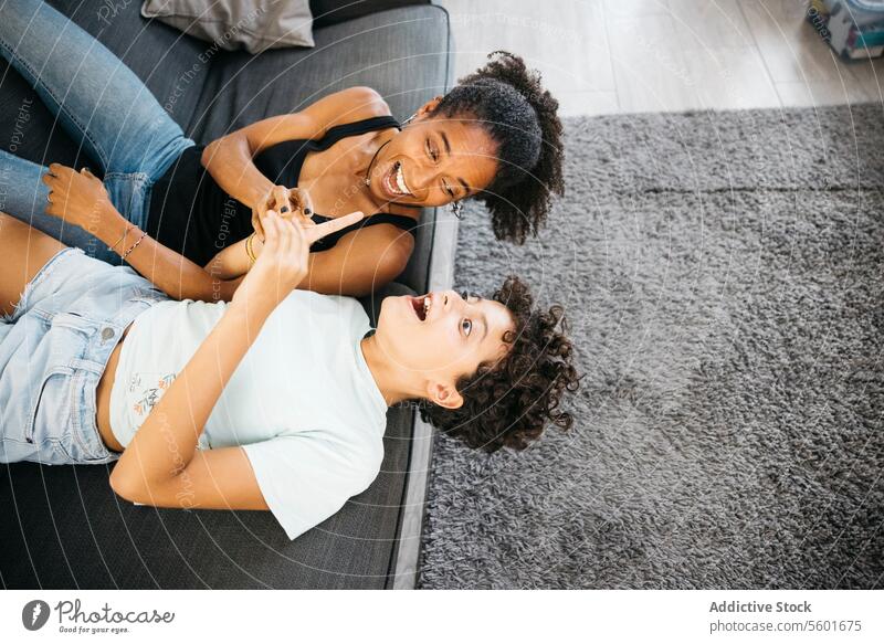 Mother and daughter playing together Family Preteen daughter Tv adorable affectionate bonding cheerful child childhood children couch cute enjoyment family life