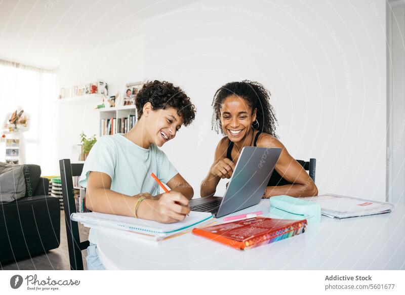 Girl doing her homework with mother Culture Family adorable affectionate after school bonding book cheerful child childhood children cute daughter day