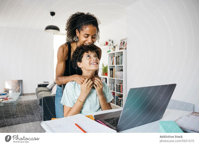 Girl doing her homework with mother Culture Family adorable affectionate after school bonding book cheerful child childhood children cute daughter day