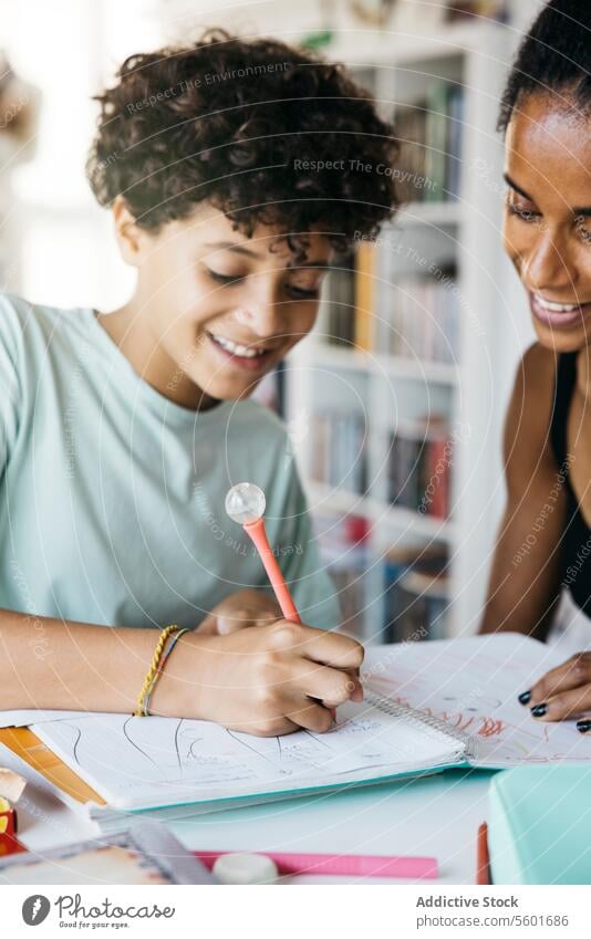 Girl doing her homework with mother Culture Family adorable affectionate after school bonding book cheerful child childhood children cute daughter day