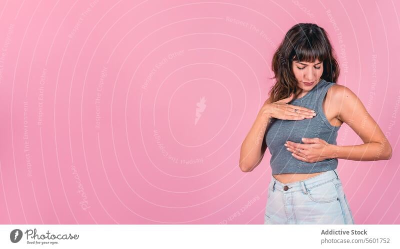 Woman doing a Breast Self-Exam over pink background. Copy space BSE Breast Cancer Awareness Breast Cancer Month Breast cancer prevention Breast health Mammogram