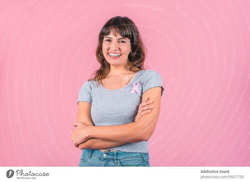 Happy woman wearing a pink breast cancer awareness ribbon while looking at camera Breast Cancer Awareness Breast Cancer Month Breast cancer prevention