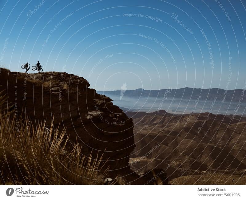 Unrecognizable cyclists on top of a mountain enjoying the scenery bike cliff valley view adventure outdoor sport cycling nature landscape travel explorer scenic