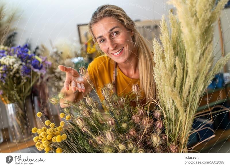 Female florist presenting a selection of dried flowers in her shop female florist florist shop floristry botanical decoration flower arrangement natural