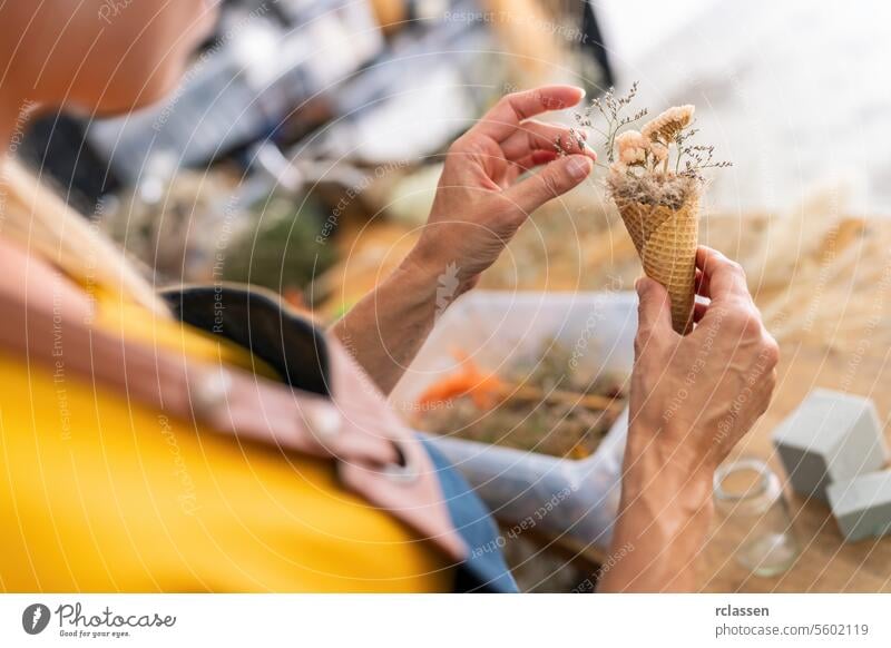 Female florist arranging dried flowers in a waffle cone at her workshop female flower arrangement handcraft decoration creative botanical diy crafting rustic