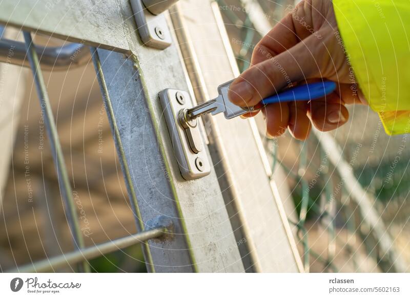 Hand unlocking metal gate with key, focus on lock and key hand security access entrance safety keyhole outdoor protection close-up selective focus person