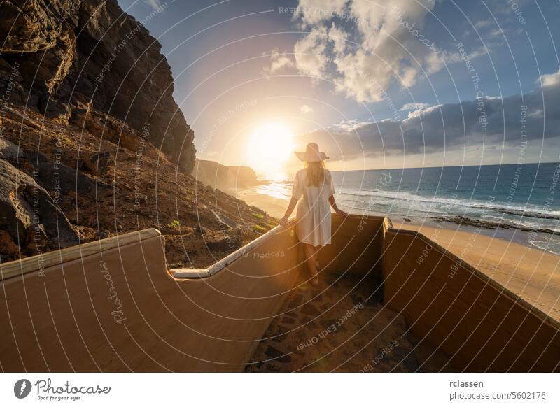 woman in a hat descending beach stairs at sunset, facing the ocean at Playa de Cofete, Fuerteventura, Canary Islands. cofete beach canarias canary fuerteventura