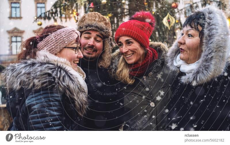 Happy friends gathered at a festive Christmas market in the snow meeting merry christmas cup hot chocolate gloves traditional mulled wine christmas market