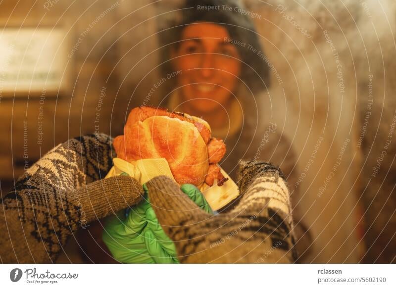 Smiling saleswoman holding bun with bratwurst or Knacker in a Booth at christmas market grilling meat grilling bratwurst roast beef winter food burger barbecue