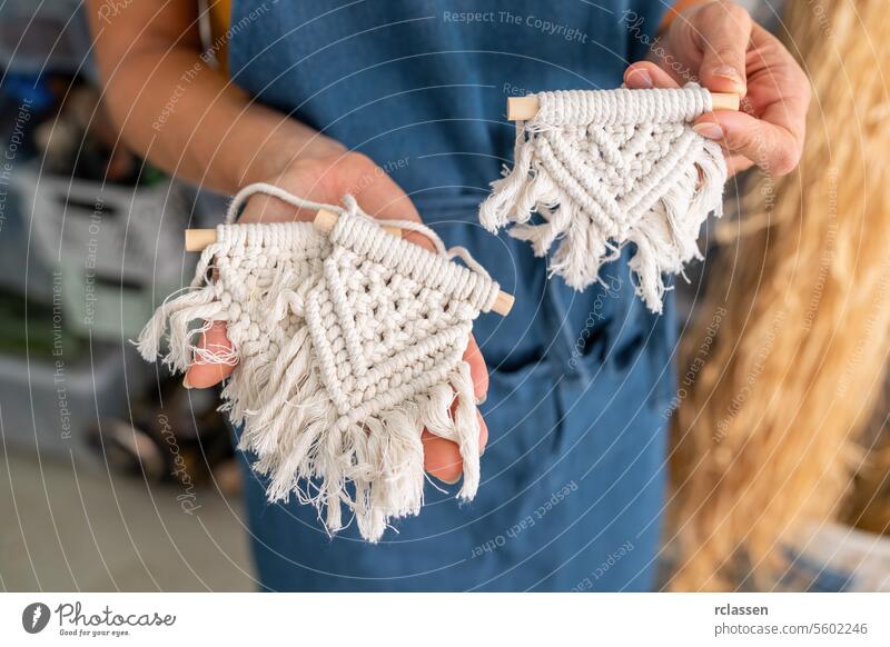 Close-up of a person holding two small macrame wall hangings close-up hand-held wall decor cotton rope fringe handcrafted texture white bohemian boho style