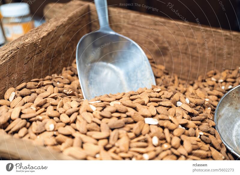 Almonds in a wooden scoop in a rustic wooden box at a Christmas market christmas christmas market almonds nuts raw almonds healthy snack organic natural