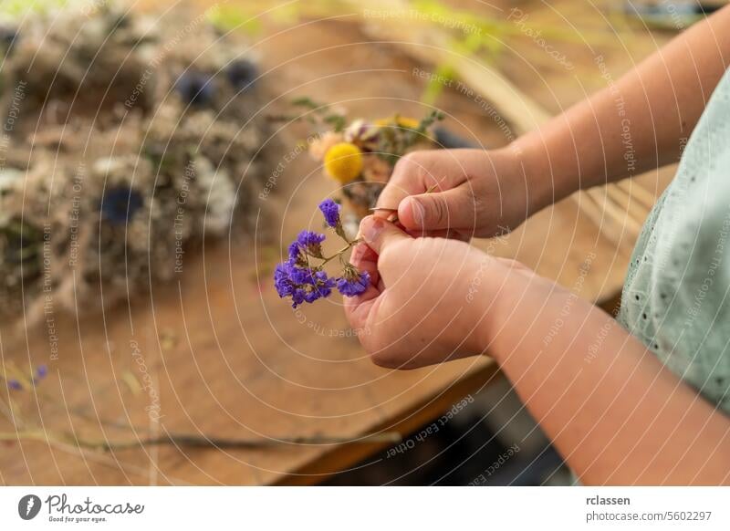 Female florist cutting the stem of a dried flower with a crafting knife on a wooden table in the workshop female florist floristry arrangement diy botanical