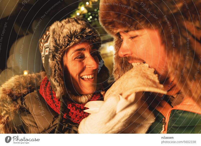 Couple enjoying a crepe together at a Christmas market, joyfully sharing the moment chocolate merry christmas gloves traditional mulled wine christmas market