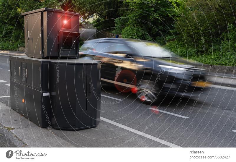 Speed enforcement camera on roadside with a car in high speed motion blur, foliage background speed camera speed enforcement fast car traffic safety