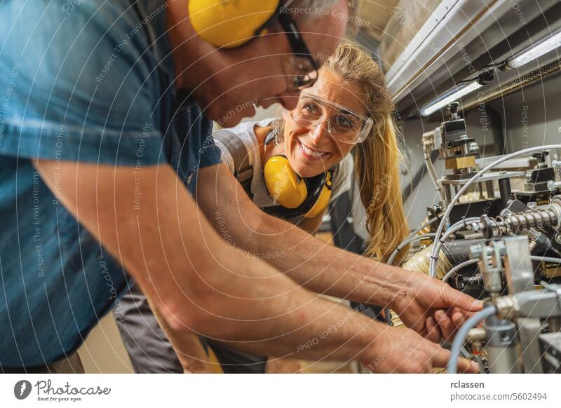 Two workers with protective gear operating machinery in a workshop carpentry teamwork safety equipment industrial manufacturing machine operation technicians