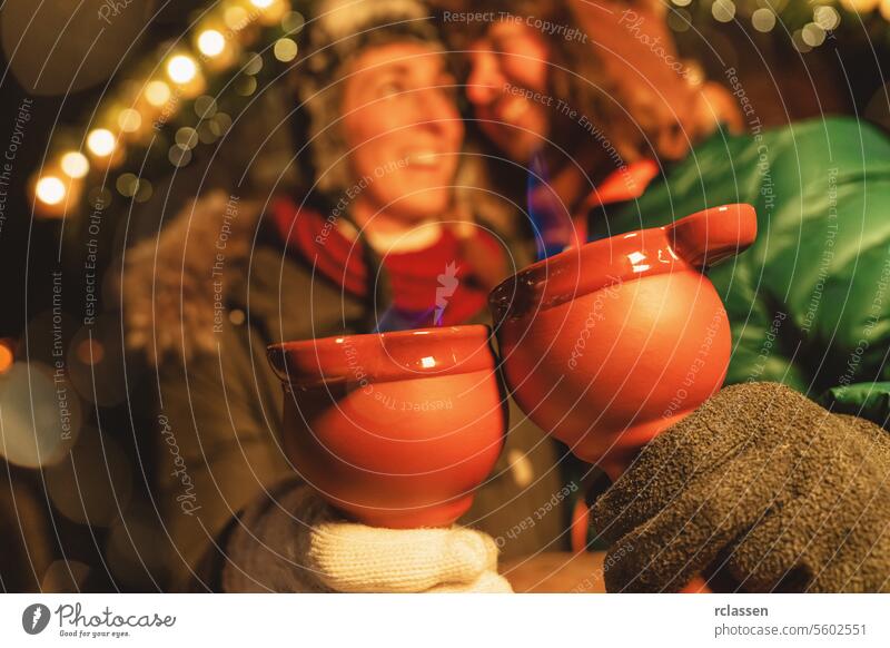 Laughing couple enjoying fire tongs punch at a Christmas market, holding steaming red mugs with blue flames. tourist mulled wine christmas market smiling couple