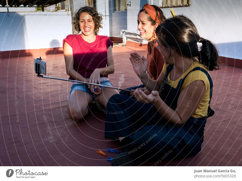 Group of women sharing laughter and happy moments as they take a selfie together on a sunny terrace, celebrating friendship and good times Friendship Selfie Fun