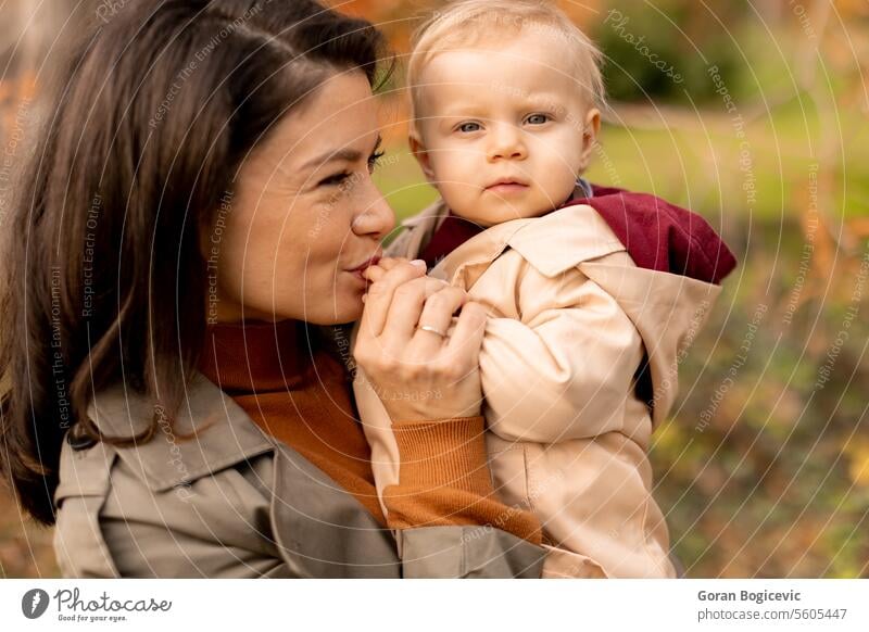 Young woman holding cute baby girl in the autumn park small caucasian mother outside daughter child little love happiness together family play mom smile season