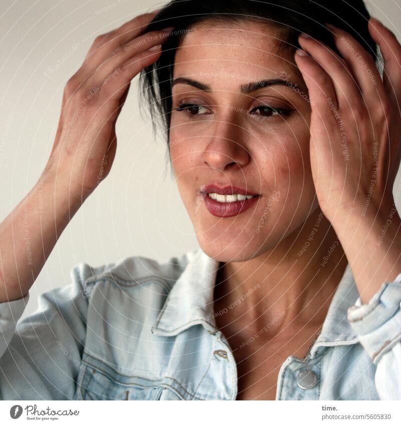 Woman, stroking her hair Jacket Jeans jacket Long-haired portrait Dark-haired Braids Upper body Arm lost in thought Smiling Half-profile hands kind Downward