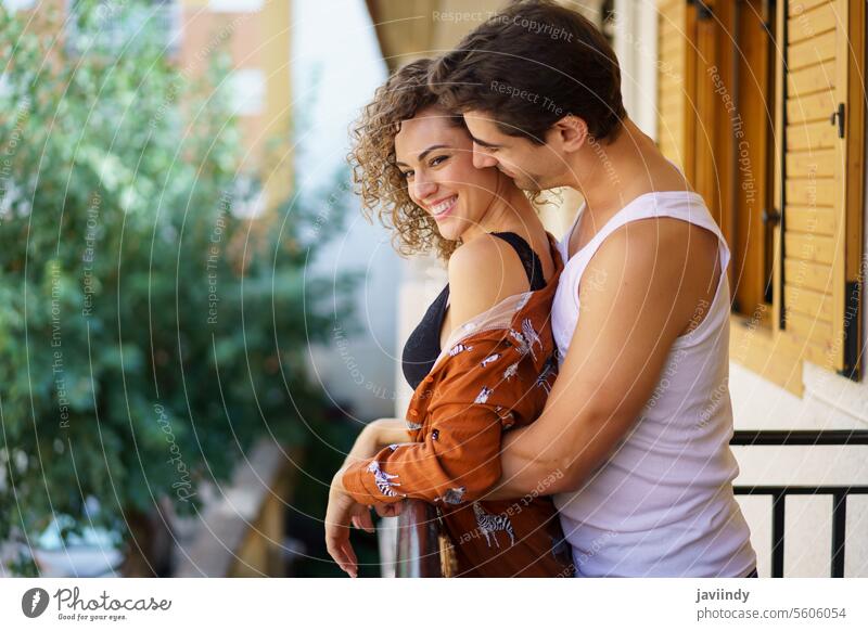 Happy couple hugging while spending time together in balcony at home romance embrace relationship positive romantic hand on waist cheerful soulmate smile young