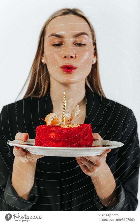 Blowing the birthday candles. Attractive young woman making a wish while holding a red cake blow celebrate attractive alone delicious blowing copy space party