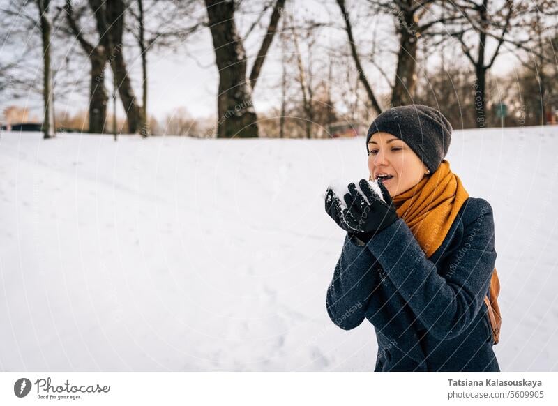 A woman blows snow off her palms in winter cold happiness happy joy female people person adult blowing coat cheerful Single person real life Contented Fun