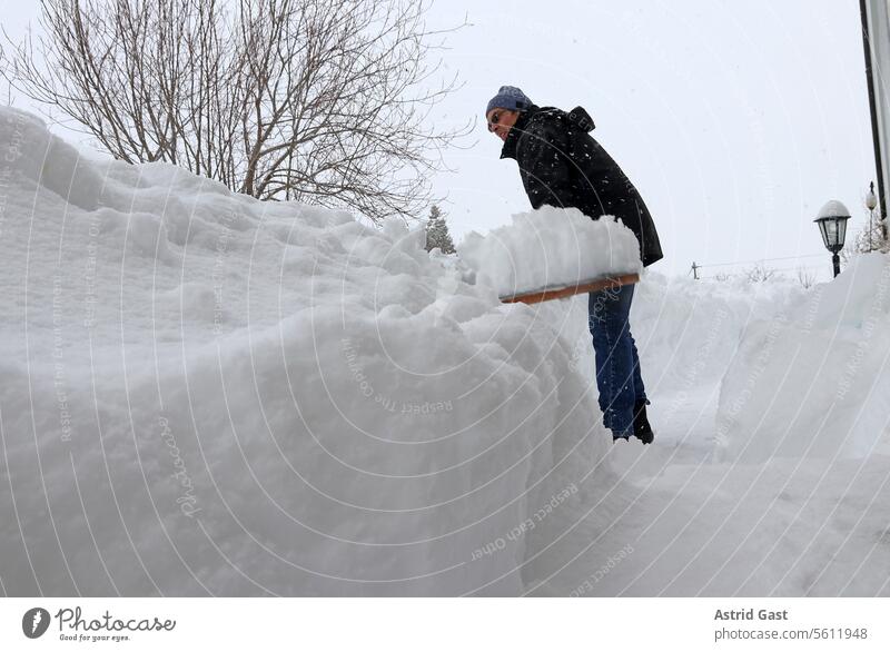 A man clears high snow from a footpath in front of a house snowplough Man Snow Winter clearance snow shovels Snow shovel Winter maintenance program snowed in