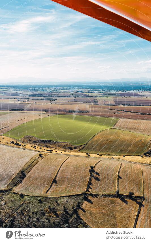 Aerial View of Patchwork Fields from an Aircraft on cloudy day aerial view patchwork fields agricultural perspective aircraft wing hues textures land mosaic