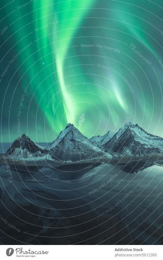 Majestic Aurora Borealis display over snow-capped peaks in Iceland aurora borealis northern lights iceland mountain night sky starry natural wonder arctic green