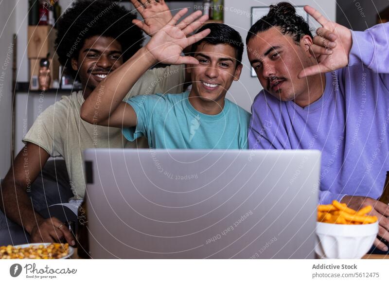 Happy friends video calling on laptop at home smile lifestyle living room gesture wave hand cheerful casual attire wireless computer leisure free time afro hair