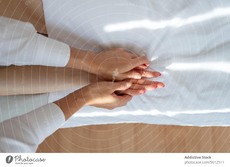 High angle crop anonymous therapist doing acupuncture massage on female client's hand on comfortable white bed in spa salon during session women high angle