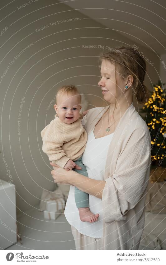 Tender moment between mother and child at Christmas baby kiss forehead christmas tree twinkling light tender love care affection family holiday celebration