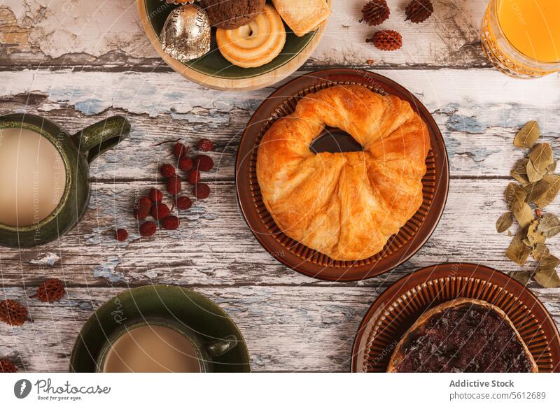 Cozy breakfast setup with pastries and beverages pastry milk orange juice table rustic cozy fresh cup glass food meal morning wood fruit grape dried fruit