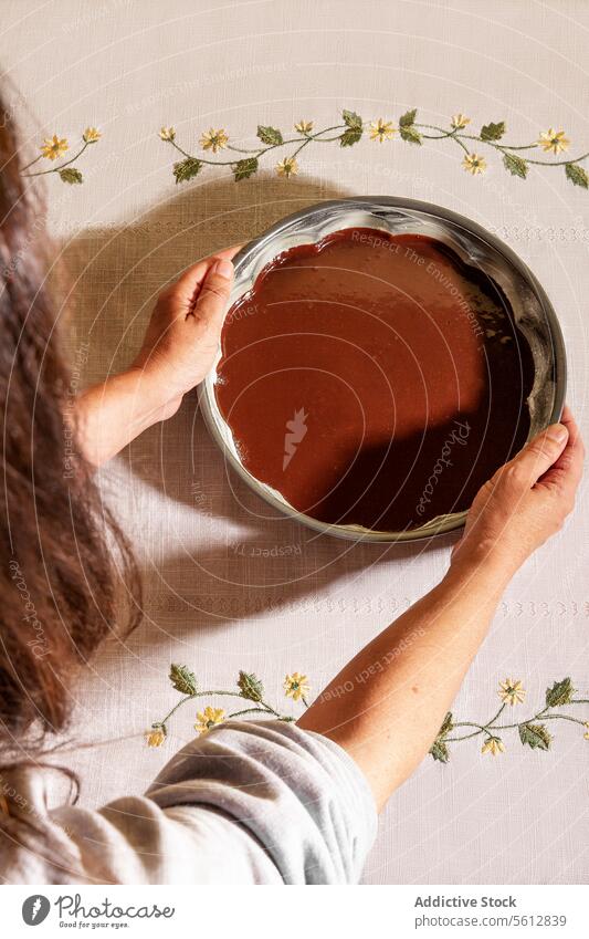 Top view of anonymous person taking bowl filled with chocolate placed on table overhead scattered flowers kitchen setting food preparation baking ingredient