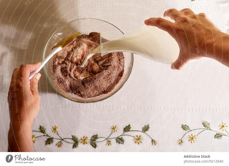 Top view of Anonymous person pouring milk into bowl with chocolate flavored on table breakfast jug floral pattern morning meal hand healthy eat food nutrition