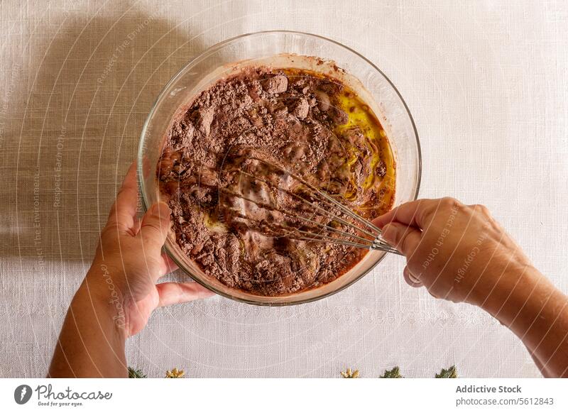 Top view of anonymous person Mixing chocolate batter in a glass bowl kitchen cooking baking whisk mixing hands overhead dessert preparation homemade recipe