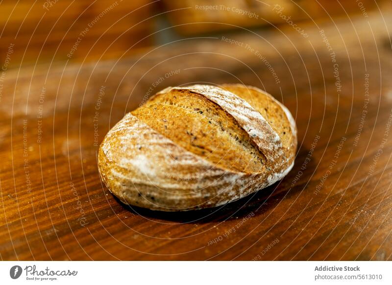 Closeup of freshly baked tasty loaf of bread with crispy crust placed on wooden table in kitchen at bakehouse closeup whole wheat healthy organic flour