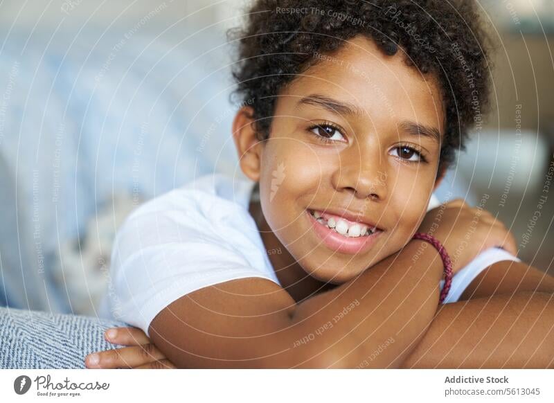 Happy boy resting on couch at home portrait smiling closeup sofa leaning living room looking happy black comfortable calm blurred background dark hair lifestyle