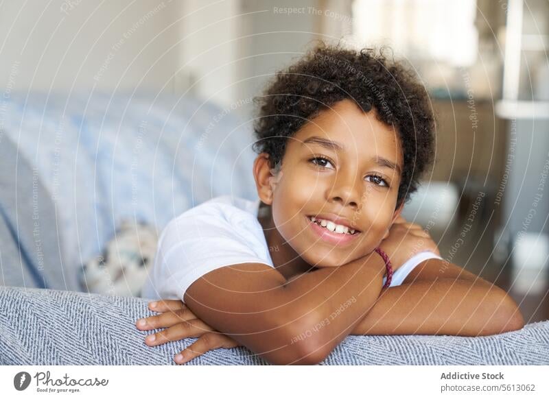 Happy boy resting on couch at home portrait smiling closeup sofa leaning living room looking happy black comfortable calm blurred background dark hair lifestyle