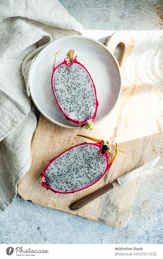 Sliced Dragonfruit on Rustic Kitchen Setting dragonfruit sliced ceramic plate rustic wooden cutting board vintage knife tropical fruit exotic seed black white