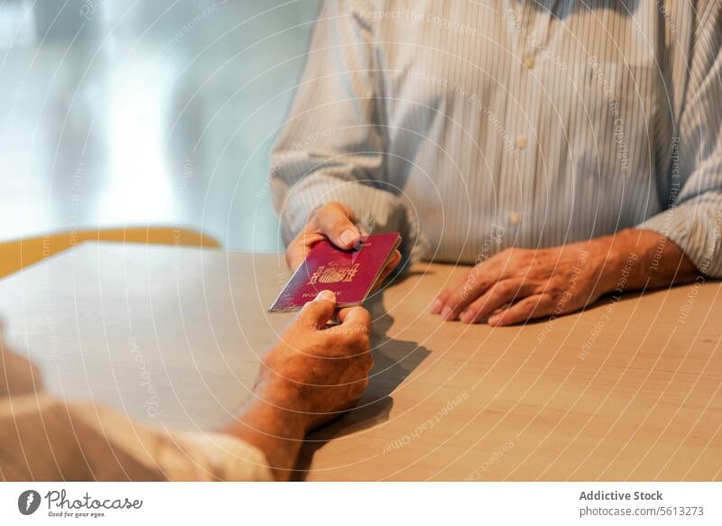 Senior man with passport on check-in senior agent hand crop white shirt receive airport vacation travel unrecognizable faceless journey tourist trip wanderlust