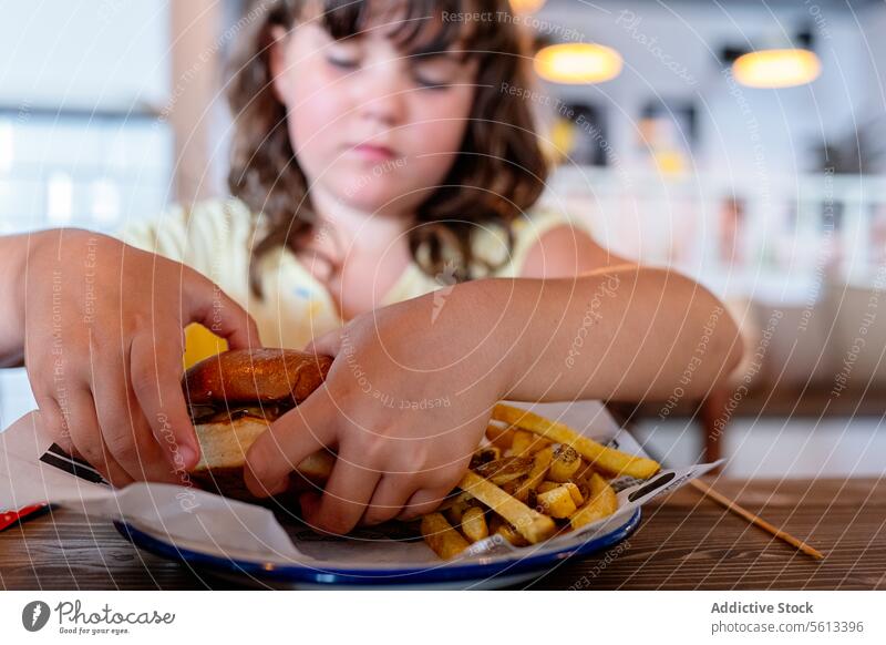 Female kid having burger in restaurant girl hungry hamburger tasty innocent table appetizing wooden meal person lifestyle child childhood little delicious