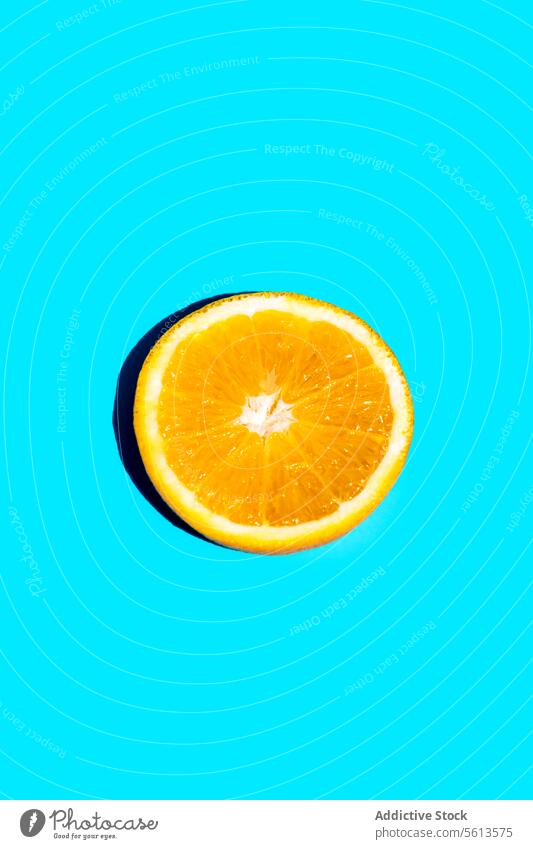 Slice of fresh orange fruit on blue background slice closeup isolated copy space citrus freshness still life shiny citron circle absence food studio zest health