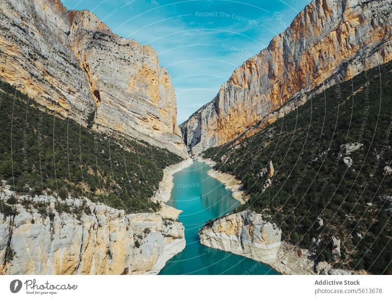 Aerial view of breathtaking scenery of calm river with blue water flowing among curvy mountainous valley with lush green trees against cloudy sky curve