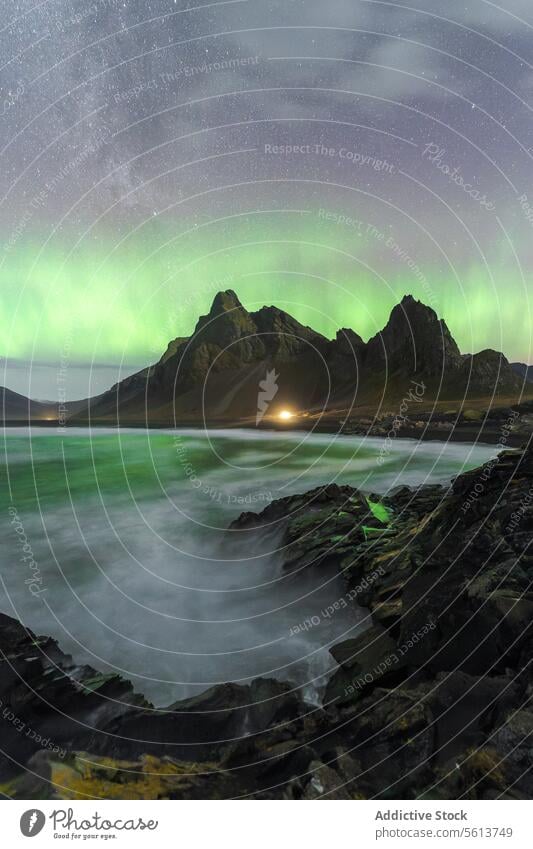 Northern lights over rocky coastline and mountain in Eystrahorn, Iceland northern lights aurora borealis rugged landscape natural wonder night sky astro