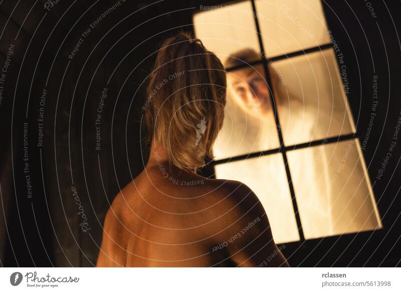 woman outside a finnish barrel sauna window smiles at her female friend inside, steam visible. happy encourage relaxation wellness warmth evening health spa