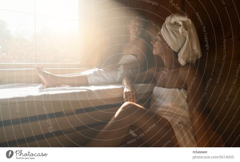 Mother and daughter in a finnish sauna, both relaxing and enjoying the warmth, sunlit window beside at spa resort child family wellness spa hotel sweat finland