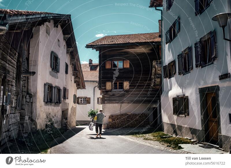 Swiss mountain village Farms Village idyll Blue sky Carrying Sunbeam White Brown Wood Street Switzerland Exterior shot Colour photo male person Sunlight